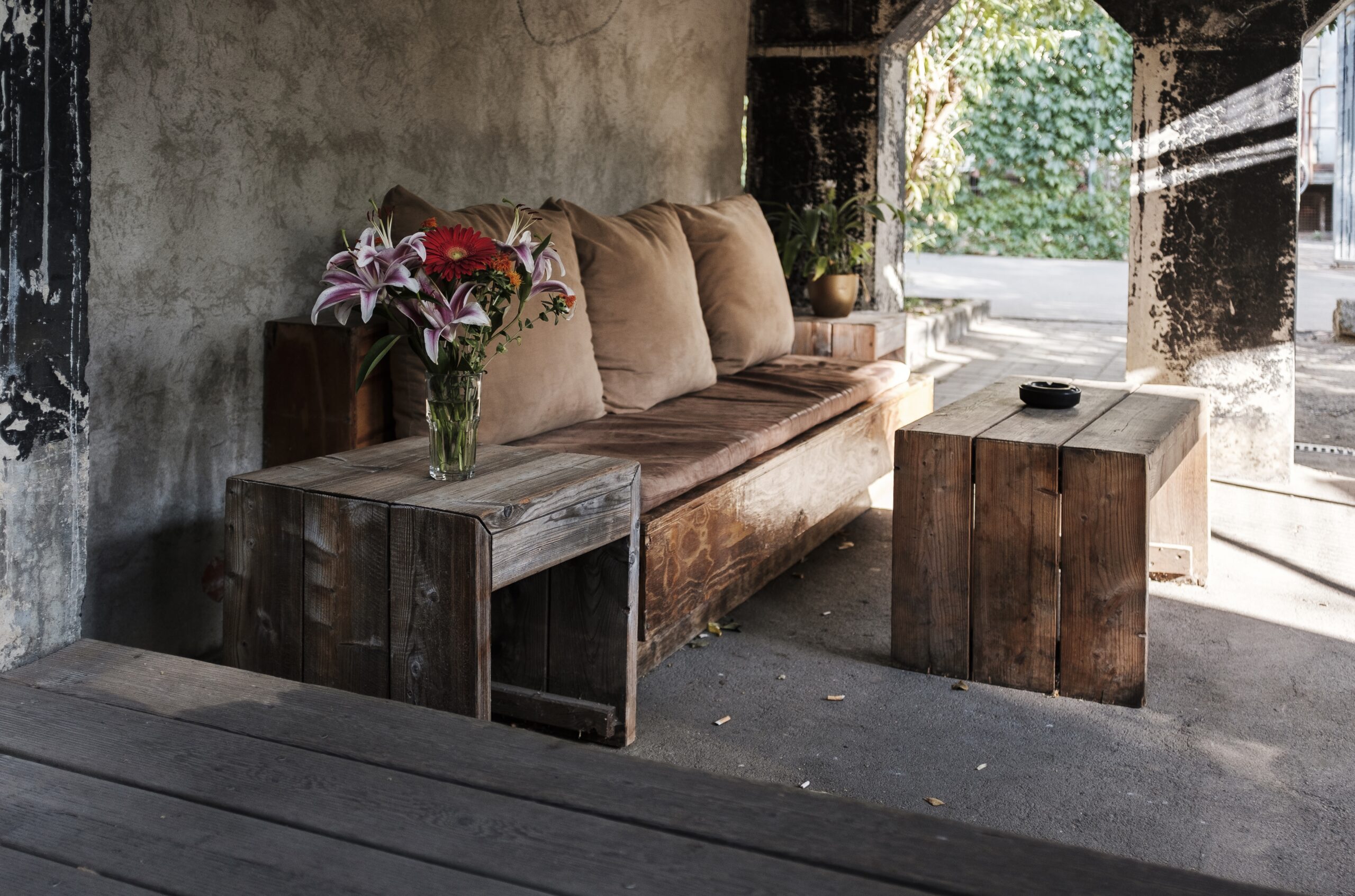 A cozy outdoor bench with pillows and a table near a house